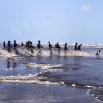 Fishermen throwing net into the sea for catching fishes at Sea view