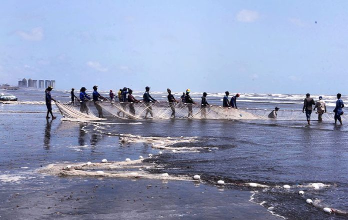 Fishermen throwing net into the sea for catching fishes at Sea view