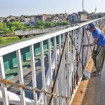 A painter busy in painting a pedestrian bridge on Islamabad Expressway
