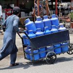 A street vendor on the way pushing a hand cart loaded with bottles and cans of clean drinking