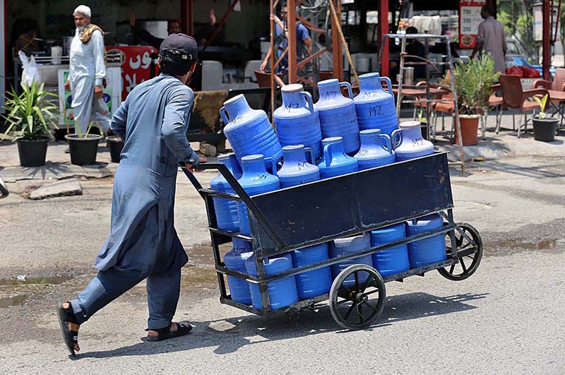 A street vendor on the way pushing a hand cart loaded with bottles and cans of clean drinking