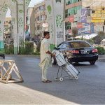 A person on the way with water bottles filled with drinking water crossing the main busy Murree Road