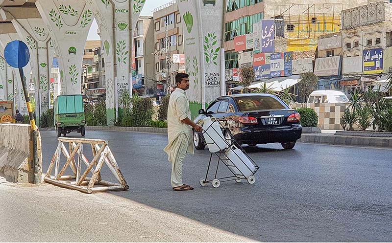 A person on the way with water bottles filled with drinking water crossing the main busy Murree Road