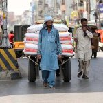 A labourer pulling a hand cart loaded with sacks at Committee Chowk