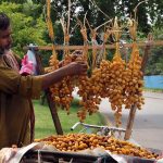 A vendor arranging and selling fresh dates on his bicycle to attract customers at roadside in the Federal Capital