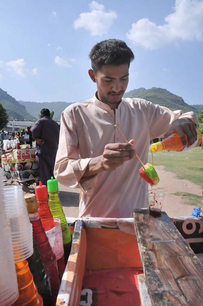 A vendor sells Ice Gola in a hot day at Shah Faisal Masjid