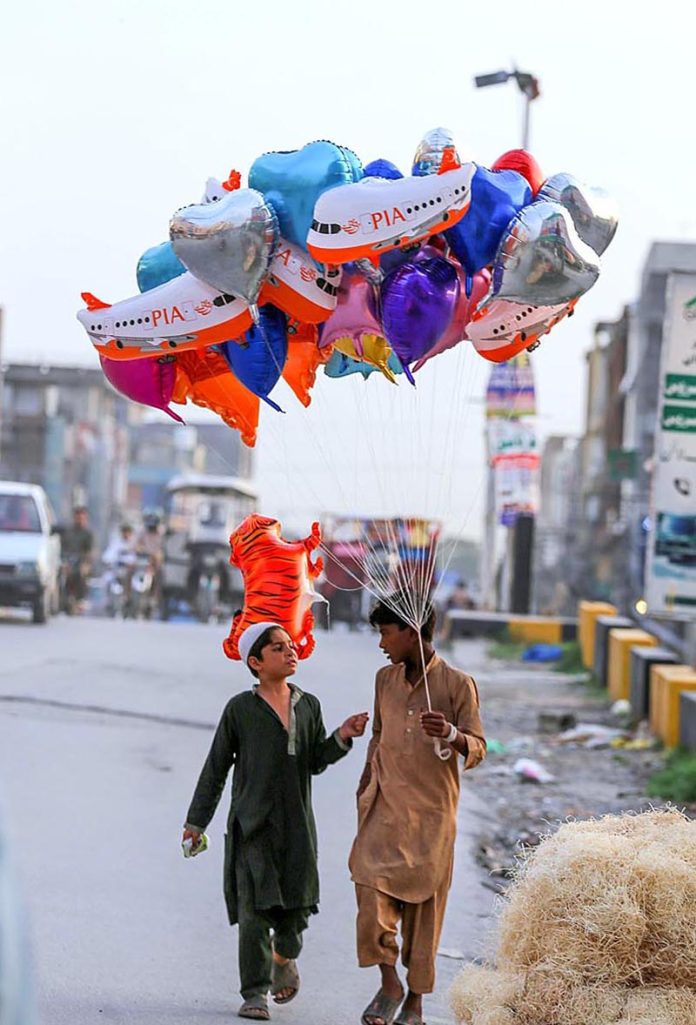 Street vendors on the way carrying different shapes balloons while looking for customers at Ghouri Town