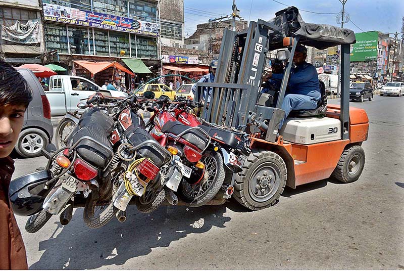 A traffic police official removing the wrongly parked motorbikes with fork lifter from "No Parking Area" at Raja Bazaar