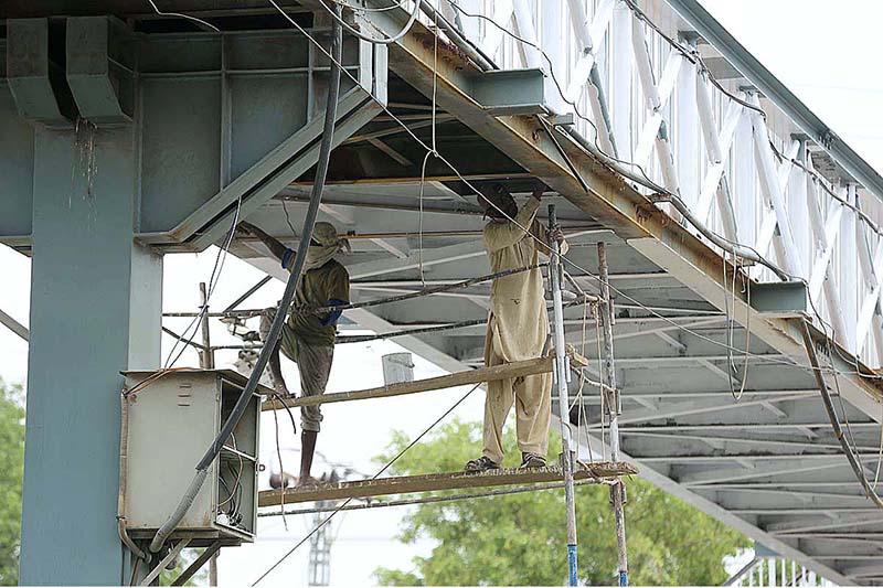 A painter busy in painting a pedestrian bridge on Islamabad Expressway