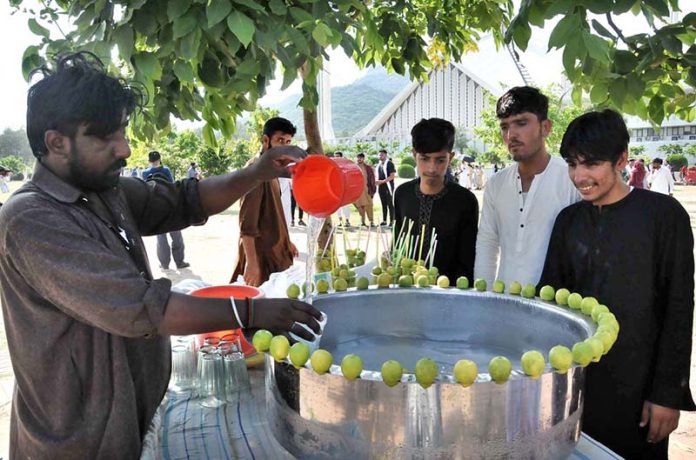 A vendor sells lamonade in a hot day at Shah Faisal Masjid