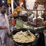 A vendor busy in frying traditional food item (samosa) for customers during rain at his shop in the Federal Capital.