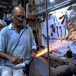 A blacksmith busy in sharpening the knives to be used by mourners oozing themselves during procession of Muharram ul Haram