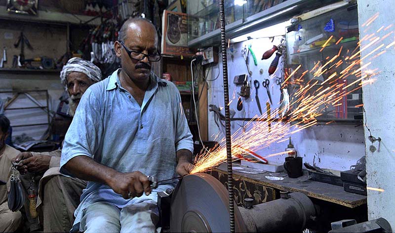 A blacksmith busy in sharpening the knives to be used by mourners oozing themselves during procession of Muharram ul Haram