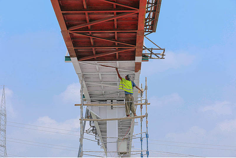 A painter busy in painting a pedestrians bridge on Islamabad Expressway
