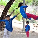 Children enjoying swing on rope tied to a tree at Latifabad