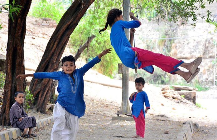 Children enjoying swing on rope tied to a tree at Latifabad