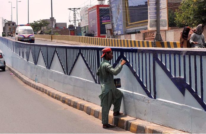 Labourer busy in coloring on the flyover wall at Nishtar road Labourer busy in coloring on the flyover wall at Nishtar road