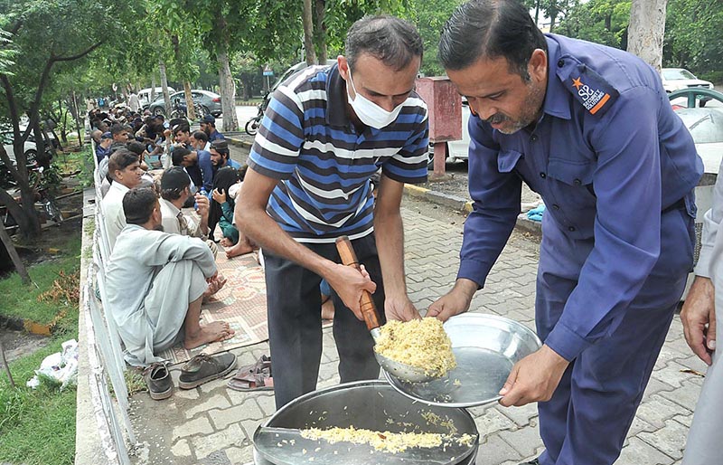 A volunteer distributing free food among deserving people as mercy at a roadside F-7 Markaz
