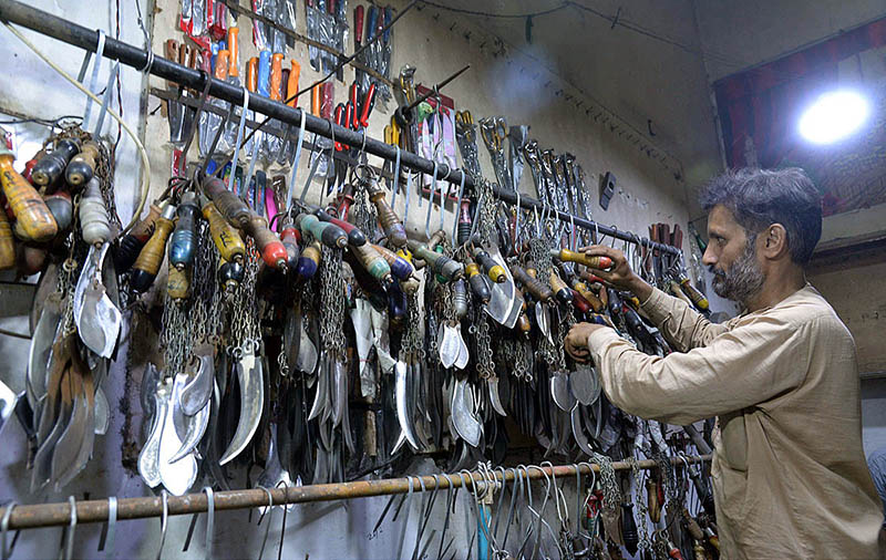 A blacksmith busy in sharpening the knives to be used by mourners oozing themselves during procession of Muharram ul Haram