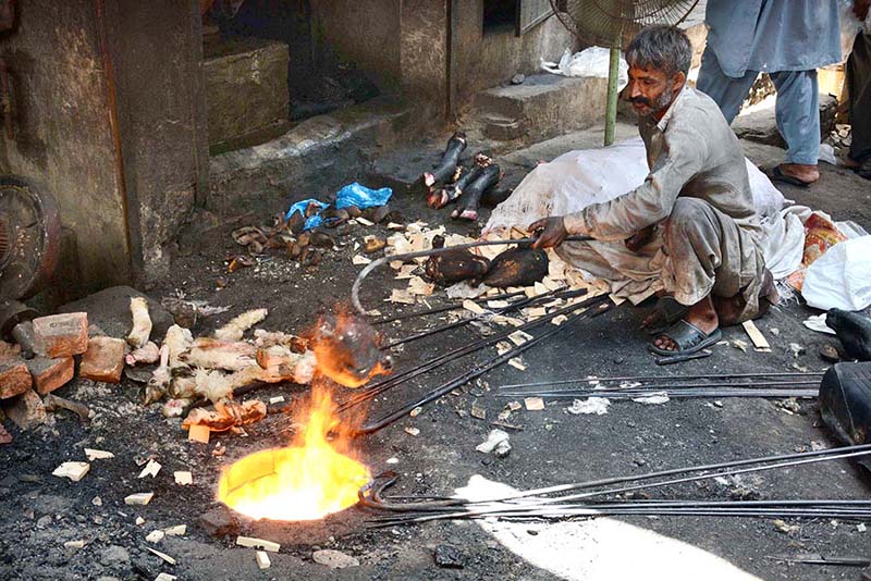 Vendor roasting sacrificial animals head and feet at Jhang Bazaar