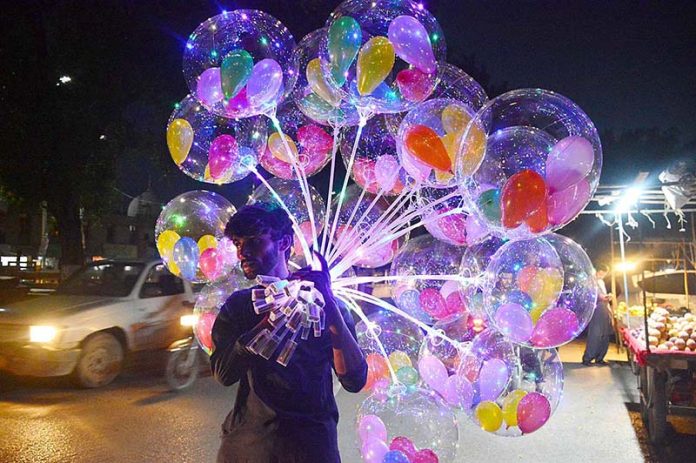 A vendor displaying colorful balloons to attract the customers at Latifabad