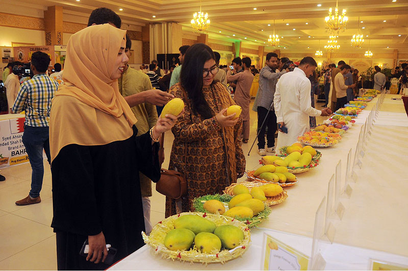 Girls viewing the displayed various varieties of mangoes during three days of ''Mango Festival 2023'' at Arena Hall DHA