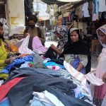 Female customers selecting and purchasing old clothes displayed by the roadside vendor to attract the customers
