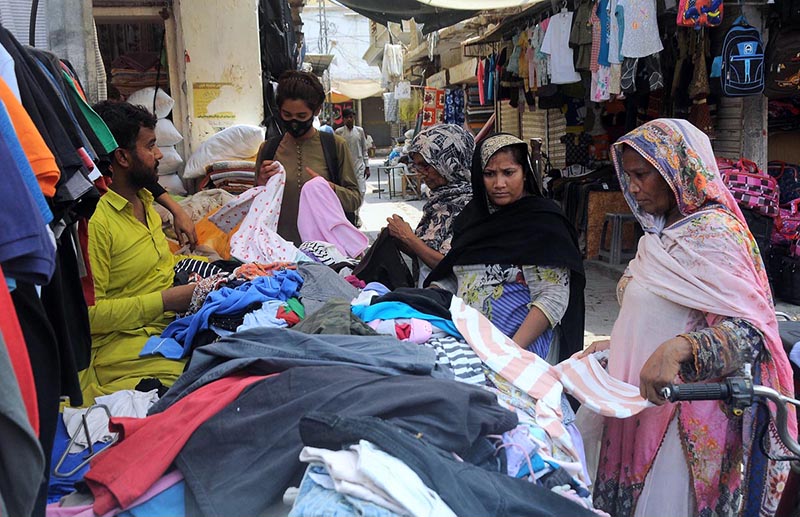 Female customers selecting and purchasing old clothes displayed by the roadside vendor to attract the customers