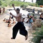 A large number of people enjoy the bathing in the Khisana Mori Canal to get relief from scorching hot weather in the city