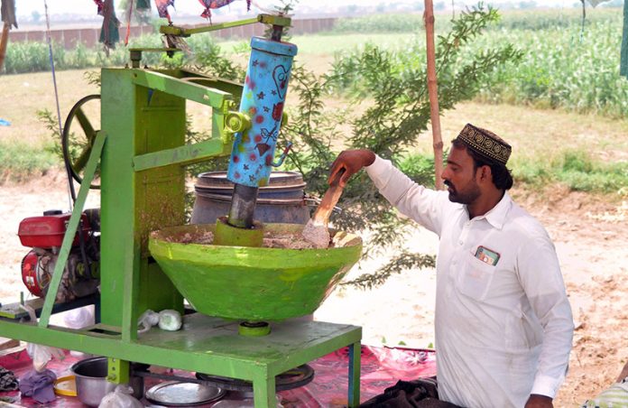 A vendor is busy in preparing a traditional summer drink (Sardai) for customers at his roadside setup