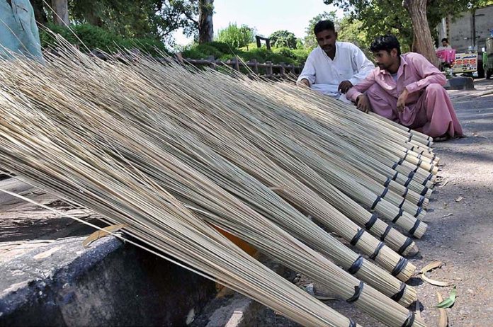 A vendor selling brooms at his roadside setup in Melody to earn some livelihood
