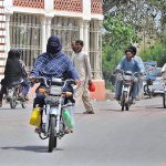 A lady riding a motorcycle heading towards her destination