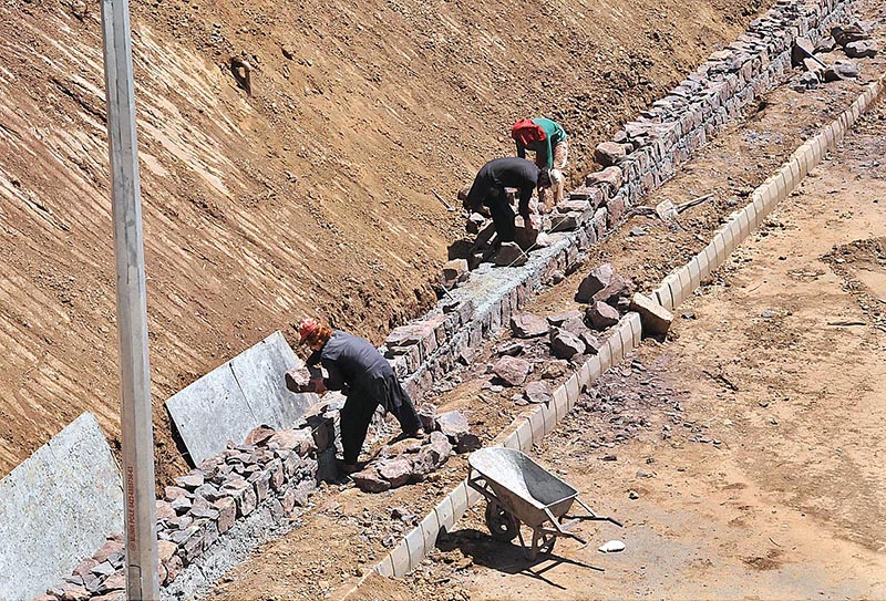 Labourers busy construction work of protection wall along Bhara Kahu Bypass
