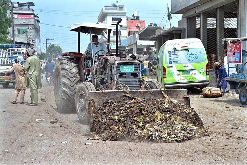 Staffer of market committee cleaning garbage with the help of tractor at Fruit and Vegetable Market.