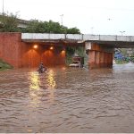 Vehicles passing through rain water accumulated on road during torrential rain since last night