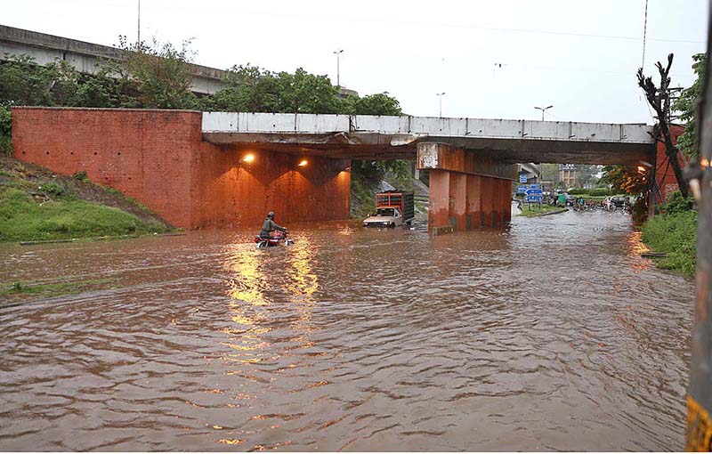 Vehicles passing through rain water accumulated on road during torrential rain since last night