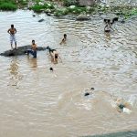 Youngsters swimming at Rawal Lake spillway water