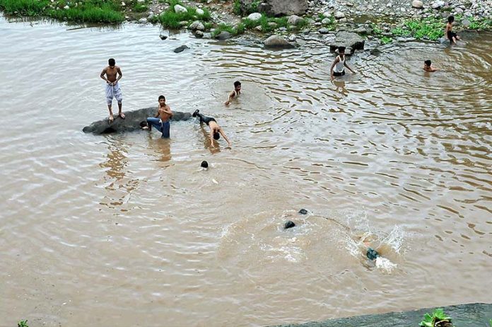 Youngsters swimming at Rawal Lake spillway water