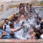 People along with children enjoying bathing in the watercourse to get some relief from hot weather in Ghulam Bhutto Village