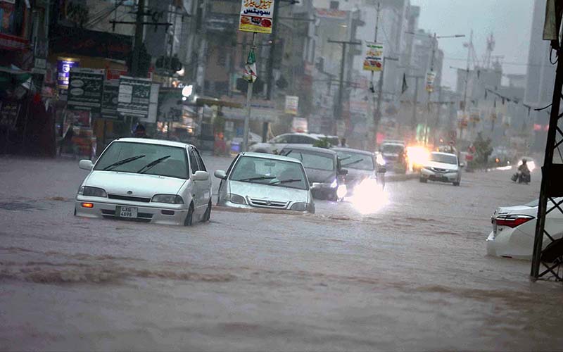 Vehicles passing through rain water accumulated on road during torrential rain since last night