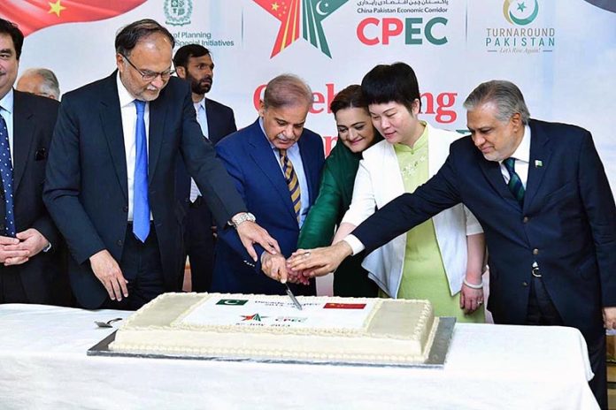 Prime Minister Muhammad Shehbaz Sharif, Chargé d'affaires of the Chinese Embassy in Islamabad Ms. Pang Chunxue and Federal Ministers cutting a cake marking the 10th anniversary of the signing of the agreement for CPEC