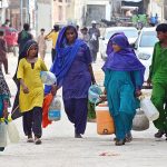 Gypsy women on the way while carrying pots for filling clean drinking water at Qasimabad