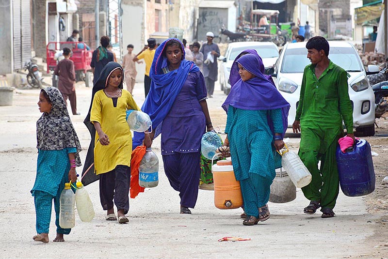 Gypsy women on the way while carrying pots for filling clean drinking water at Qasimabad