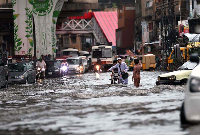 Vehicles passing through rain water accumulated on road during torrential rain since last night