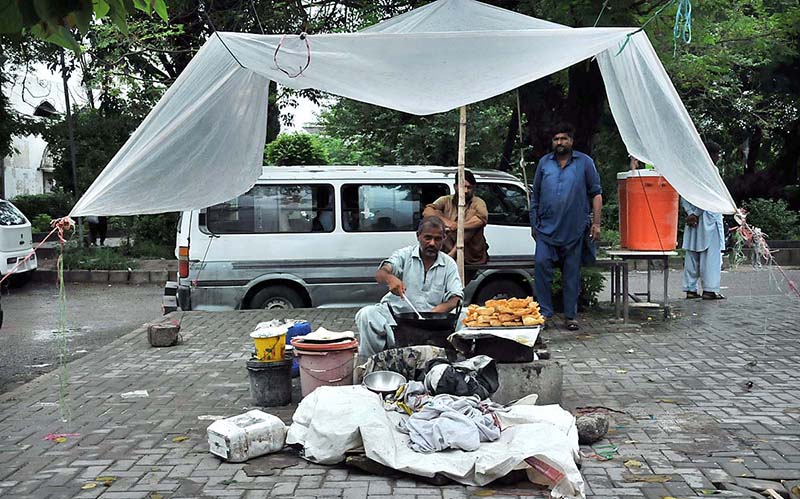 A vendor busy in frying samosa for customers at bus stop