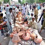 Vendors displaying the clay made pots to attract the customers on footpath at Latifabad
