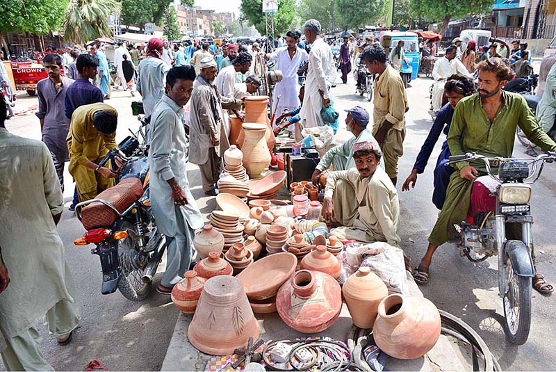 Vendors displaying the clay made pots to attract the customers on footpath at Latifabad