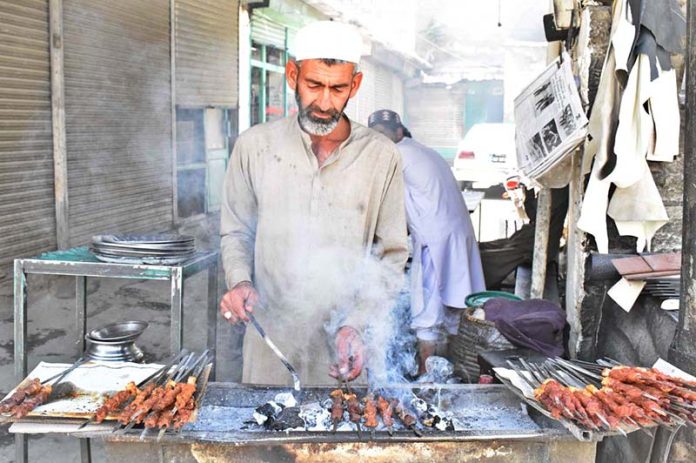 A vendor busy in preparing traditional Seekh Kabaab on 3rd day of Eidul Adha at his road side setup to attract customers