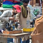 Mechanic busy in repairing sewing machine of woman customer at his roadside setup