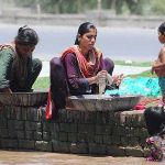 Gypsy ladies washing clothes while sitting on the edge of Canal